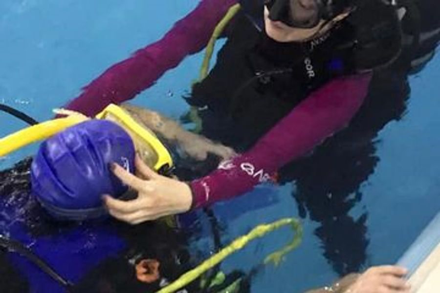 Instructor helping a young diver in the pool